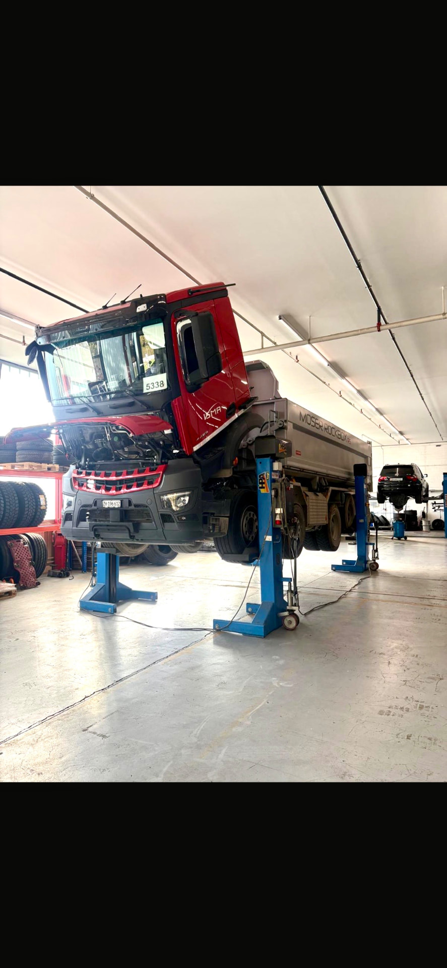 Roter Lastwagen auf der Hebebühne in der Werkstatt